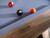 Detail close-up of the Nixon Billiards Desyn Slate Pool Table featuring the engraved Nixon Billiards logo on the side apron. Captures the subtle branding, premium wood craftsmanship, and clean finish of the Gray Walnut frame — reinforcing the table’s designer pedigree and authenticity.