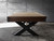 Wide-angle lifestyle view of the Portland Slate Pool Table by Nixon Billiards, fully outfitted with the optional dining top in place, showcasing the table’s furniture-grade functionality and bold industrial styling. The dining surface covers the entire playfield with a seamless fit, while the matte black X-style steel legs provide sculptural contrast against the rustic hardwood cradle. This staged shot, captured in a contemporary interior with ambient lighting and open space, presents the Portland as a true dual-purpose centerpiece—perfect for entertaining, dining, or a statement look in any luxury game room. Styled exclusively by Sawyer Twain.