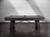 A high-quality side view of the Isaac Slate Pool Table in Distressed Black & Gold, captured from a professional photo shoot. This angle showcases the sleek lines of the table, with its distressed black wood finish and gold accents standing out. The oversized gold turnbuckles and professional-grade features are clearly visible, offering a detailed view of the rugged yet refined design that blends modern industrial style with timeless elegance.