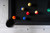 Angled top-down lifestyle image of the Alta Slate Pool Table by American Heritage Billiards, featuring a close-up of the corner pocket area in Sawyer Twain’s exclusive White Wash on Ash finish. The shot highlights the soft Teflon-coated Championship Invitational felt, genuine leather drop pocket, and custom black diamond rail sights set into the solid ash rails. A few of the Sawyer Twain Luxury Trophy Kit balls rest in play, showcasing the table’s premium surface and designer-level detailing from above.

