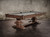 The table is styled in a residential space, giving context to how it anchors the room. Warm lighting and organic textures enhance the tone of the Distressed Brown finish.