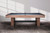 A lifestyle side profile of the Vancouver Slate Pool Table by American Heritage Billiards, styled in a warm, contemporary interior with soft lighting and natural textures. The reeded wood legs and exclusive Honey Ash finish take center stage, while the dining top adds versatility to the space. This image is perfect for shoppers exploring “luxury game room furniture with dining option,” “modern slate pool table for open-concept interiors,” or “designer convertible pool tables with bench seating.”

