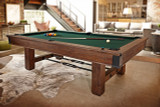 Featuring the 8' Brunswick Canton Slate Pool Table in Black Forest, this lifestyle shot places the table in a bright, contemporary game room setting with light wood flooring, neutral textiles, and large windows. This image targets upscale homeowners seeking to integrate rustic game room elements into modern spaces.